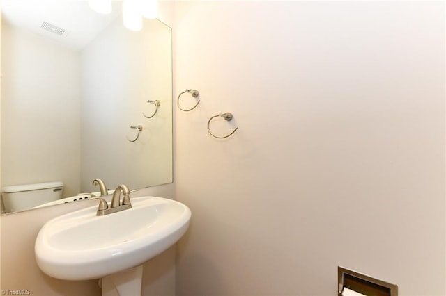 half bathroom with visible vents, a sink, and toilet