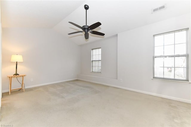 spare room with lofted ceiling, baseboards, light carpet, and visible vents