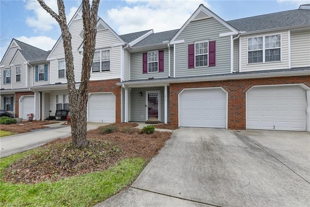 townhome / multi-family property with brick siding, driveway, and an attached garage