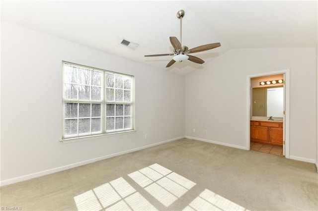 unfurnished bedroom featuring lofted ceiling, light carpet, a sink, visible vents, and baseboards