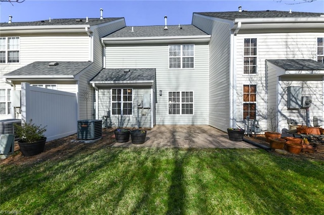 back of property featuring a lawn, a patio, roof with shingles, fence, and central AC