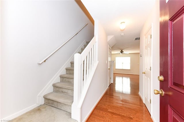 staircase featuring visible vents, wood finished floors, a ceiling fan, and baseboards