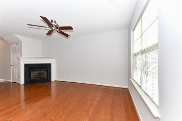 unfurnished living room with a fireplace with flush hearth, baseboards, and wood finished floors