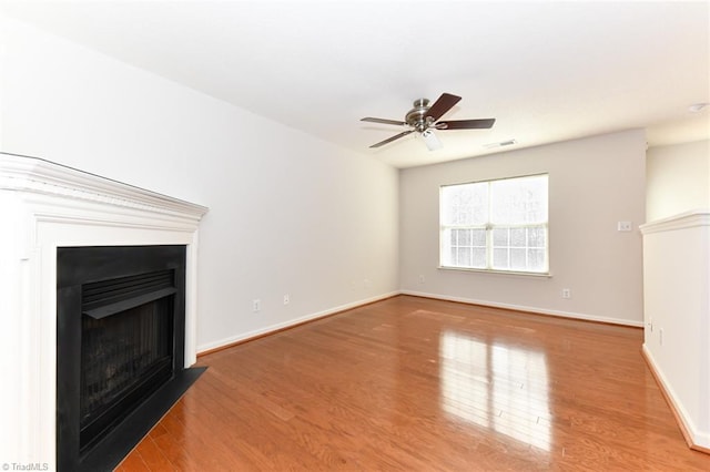 unfurnished living room featuring baseboards, visible vents, a fireplace with flush hearth, ceiling fan, and wood finished floors