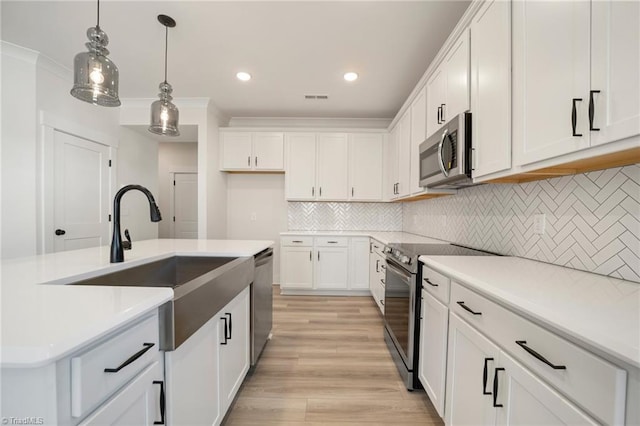 kitchen featuring white cabinets, decorative light fixtures, stainless steel appliances, tasteful backsplash, and sink