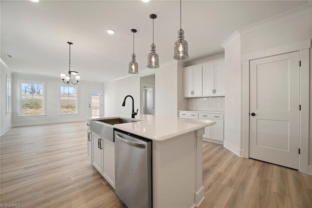 kitchen with stainless steel dishwasher, a kitchen island with sink, sink, and white cabinetry