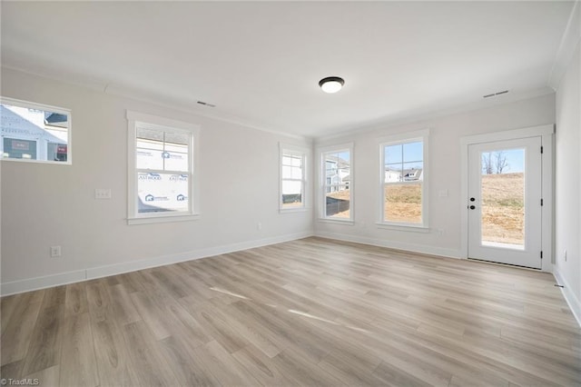 spare room featuring light hardwood / wood-style floors, crown molding, and a healthy amount of sunlight