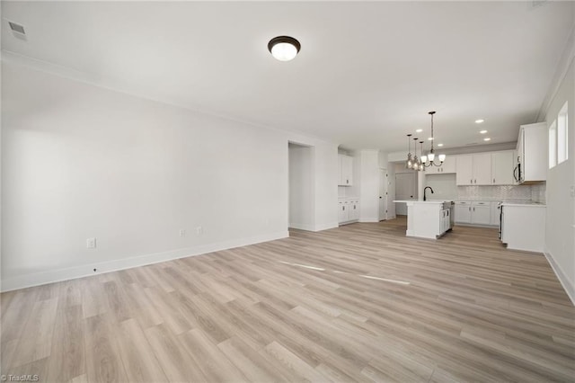 unfurnished living room with light hardwood / wood-style floors, sink, crown molding, and a chandelier