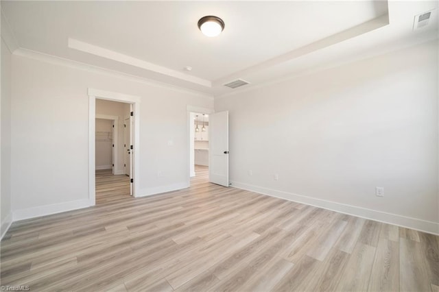 unfurnished bedroom featuring a tray ceiling, light hardwood / wood-style flooring, and ornamental molding