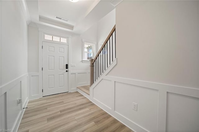 foyer with light wood-type flooring and a tray ceiling