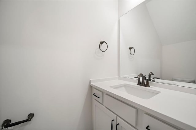 bathroom with toilet, vanity, and vaulted ceiling