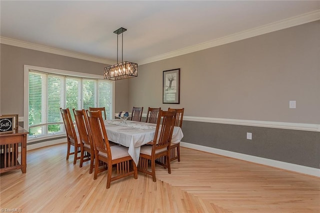 dining space featuring ornamental molding, an inviting chandelier, and light wood-type flooring