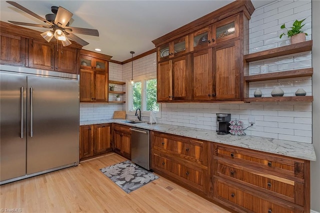 kitchen featuring stainless steel appliances, light stone countertops, backsplash, and light hardwood / wood-style floors