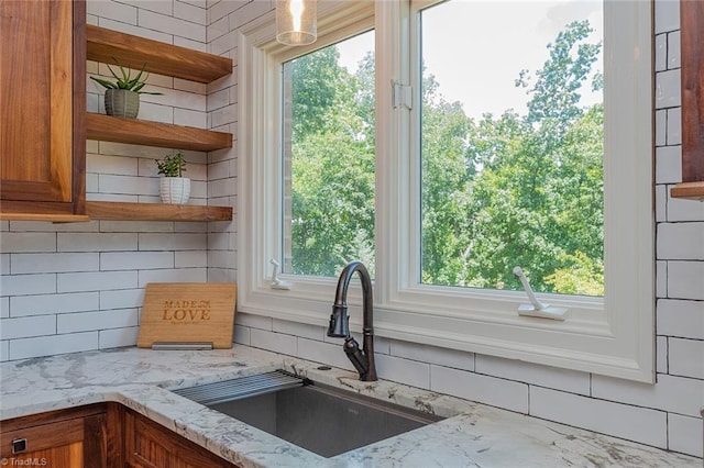 kitchen featuring light stone countertops, sink, and decorative backsplash