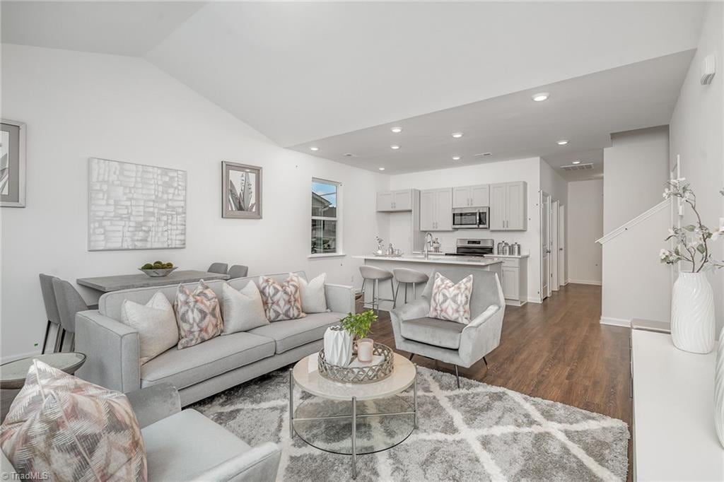 living room featuring vaulted ceiling, sink, and dark hardwood / wood-style flooring