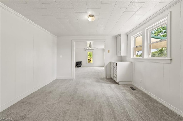 spare room featuring visible vents, a ceiling fan, light carpet, and crown molding