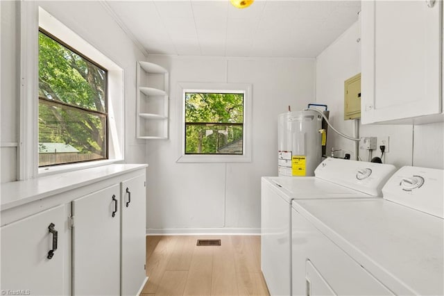 washroom with washing machine and clothes dryer, baseboards, electric water heater, light wood finished floors, and cabinet space