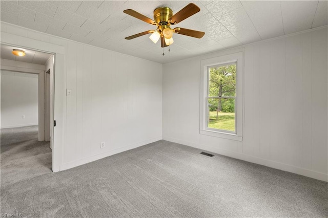 carpeted empty room with a ceiling fan, visible vents, and baseboards