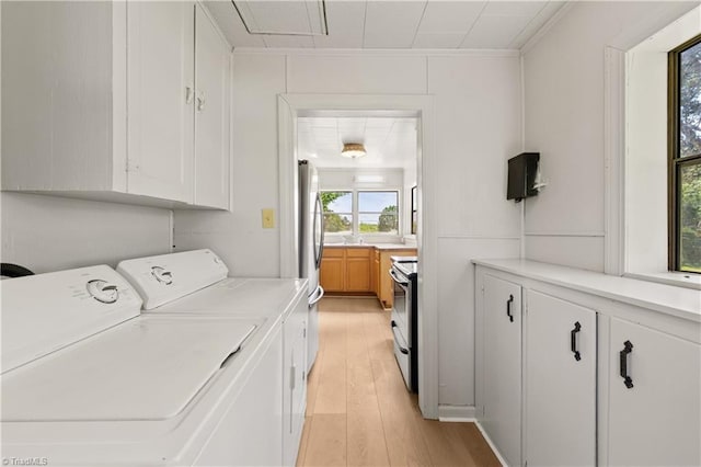 laundry area with attic access, cabinet space, washing machine and clothes dryer, and light wood-style floors