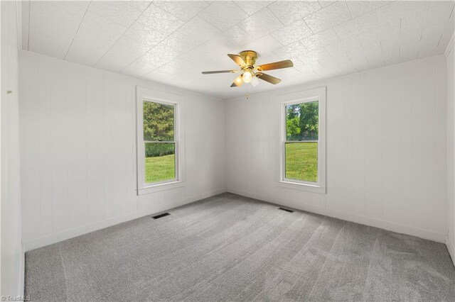 carpeted empty room featuring ceiling fan, visible vents, and baseboards
