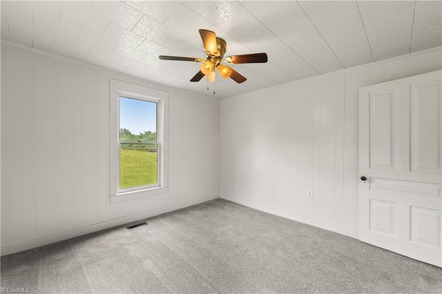 carpeted spare room featuring visible vents, ceiling fan, and baseboards