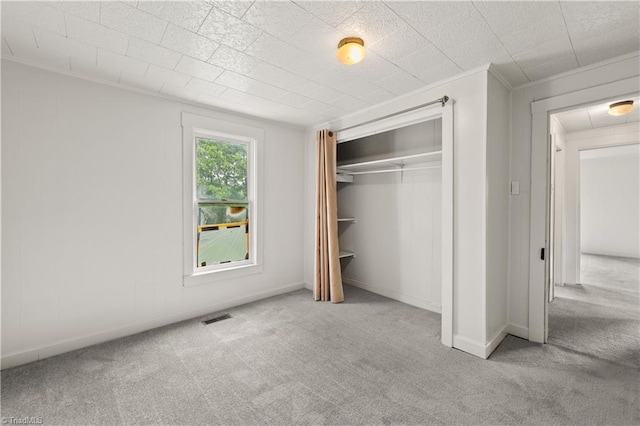 unfurnished bedroom with a closet, carpet flooring, baseboards, visible vents, and crown molding