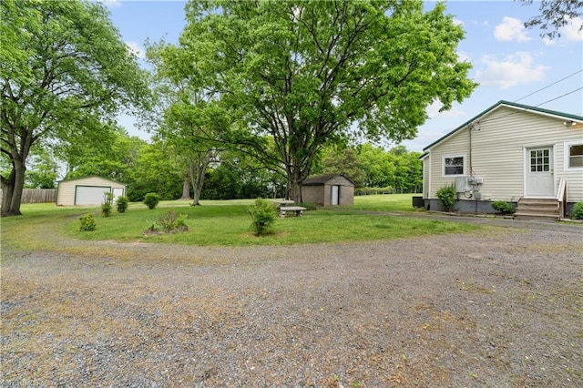 view of yard with a garage, entry steps, a shed, and an outbuilding