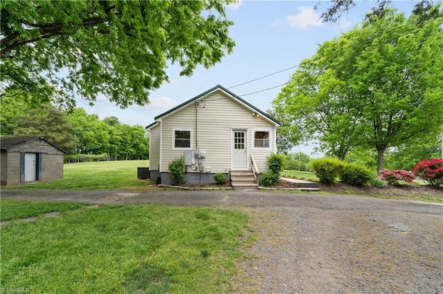 bungalow with a front lawn, central AC unit, an outdoor structure, a shed, and entry steps