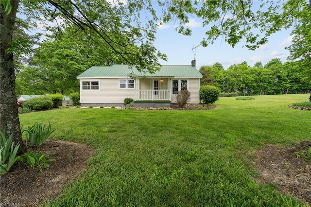 view of front of home featuring a porch, a front yard, metal roof, and a chimney