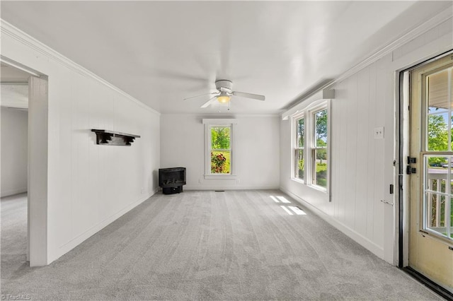 unfurnished living room with carpet flooring, baseboards, ceiling fan, and crown molding