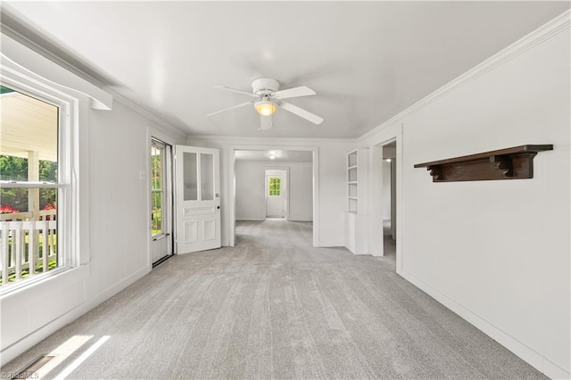 spare room with light colored carpet, ceiling fan, a healthy amount of sunlight, and crown molding