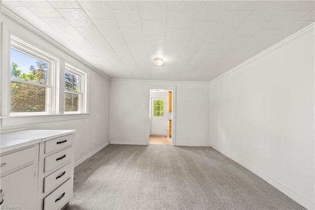spare room with light colored carpet, ornamental molding, and baseboards