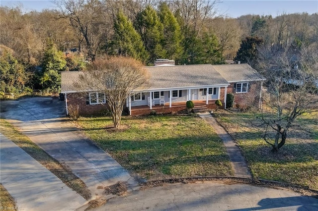 single story home featuring brick siding, a front yard, covered porch, and driveway