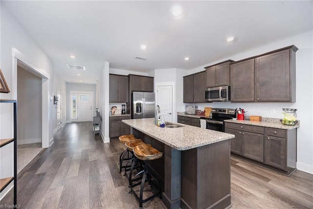3903 Sudley Pt Unit 18, Jamestown, NC 27282 - kitchen featuring stainless steel appliances, dark brown cabinetry, dark wood-style floors, a kitchen bar, and light stone counters