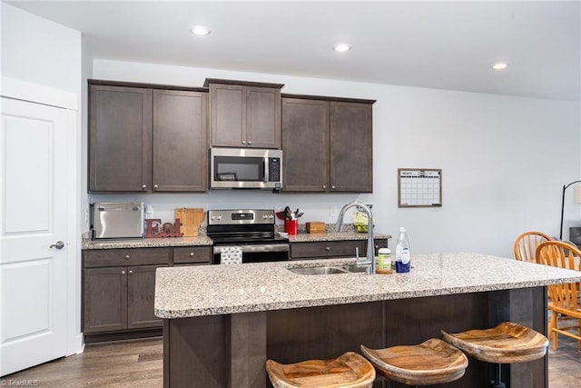 3903 Sudley Pt Unit 18, Jamestown, NC 27282 - kitchen with stainless steel appliances, a breakfast bar area, dark brown cabinetry, dark wood-style flooring, and a kitchen island with sink