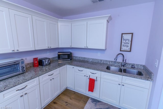 kitchen featuring wood-type flooring, sink, and white cabinets