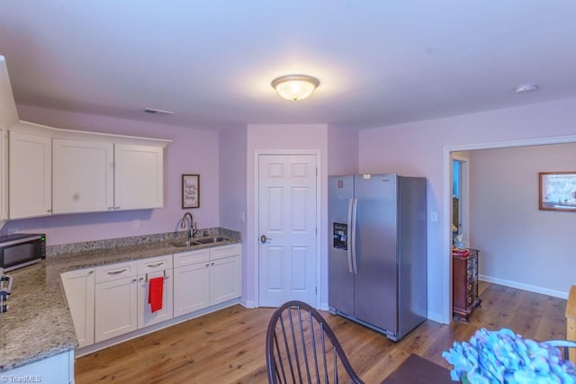 kitchen with stainless steel appliances, sink, white cabinets, and light hardwood / wood-style floors