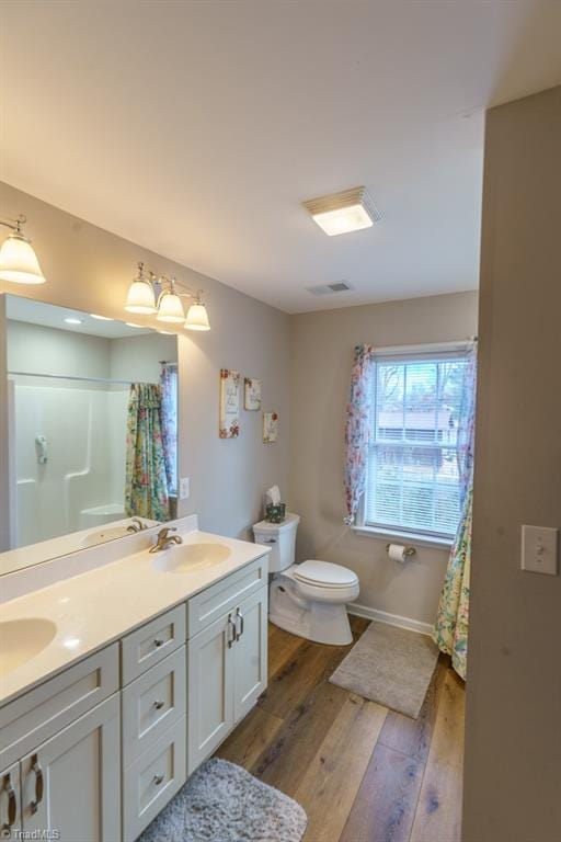 bathroom with a shower with curtain, wood-type flooring, toilet, and vanity