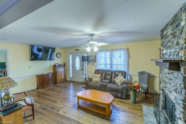 living room with hardwood / wood-style flooring, ceiling fan, ornamental molding, and a fireplace