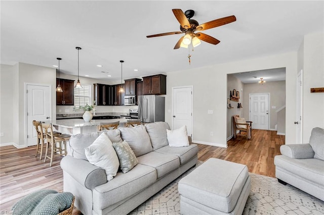 living area featuring ceiling fan, recessed lighting, baseboards, and light wood-style floors