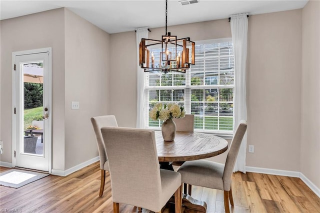 dining space featuring baseboards, a wealth of natural light, an inviting chandelier, and light wood-style flooring