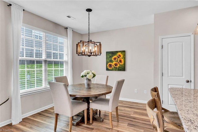 dining room with a wealth of natural light, light wood-style floors, baseboards, and a notable chandelier