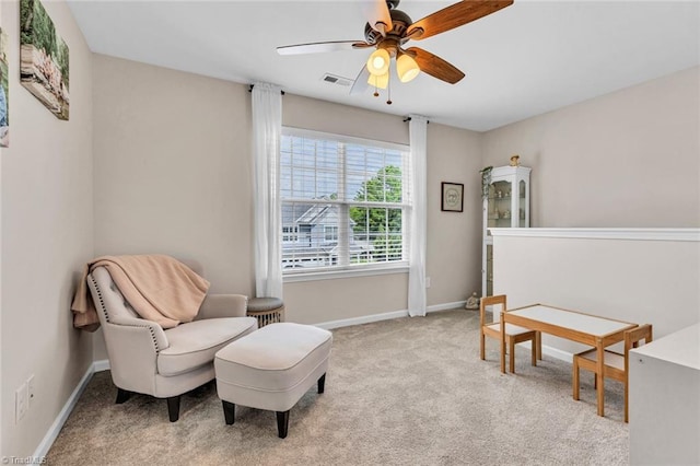 living area featuring a ceiling fan, baseboards, visible vents, and light colored carpet