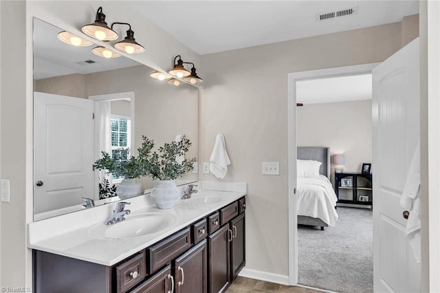 ensuite bathroom featuring double vanity, connected bathroom, visible vents, and a sink