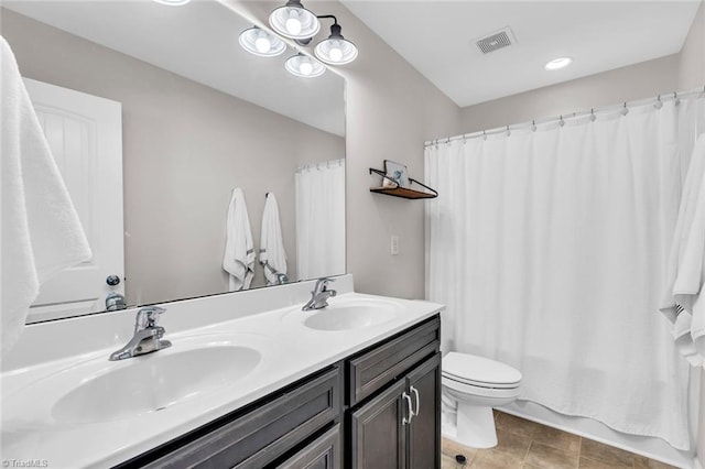 bathroom featuring toilet, visible vents, a sink, and double vanity