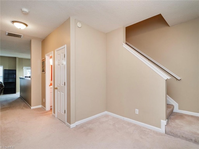 interior space featuring light colored carpet and a textured ceiling