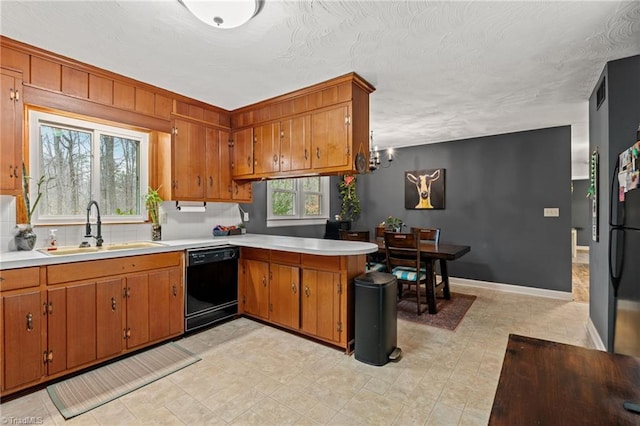 kitchen with a sink, brown cabinets, black dishwasher, and a peninsula