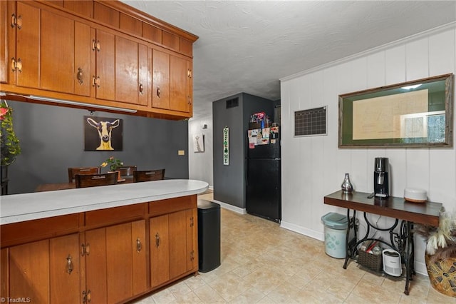 kitchen featuring brown cabinets, light countertops, and freestanding refrigerator