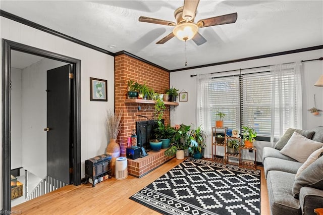 living room featuring wood finished floors, a ceiling fan, ornamental molding, and a fireplace