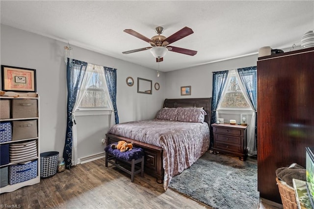 bedroom with a ceiling fan, wood finished floors, baseboards, and a textured ceiling